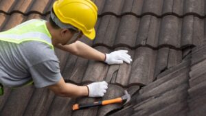 A man performing roof repairs with a hammer.