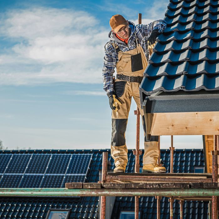 A man is working on a roof with solar panels.